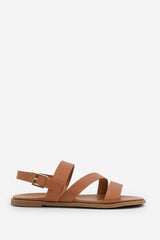 NESSA WIDE FIT FLAT SANDALS WITH CROSS OVER STRAP AND BUCKLE CLOSURE IN TAN FAUX LEATHER