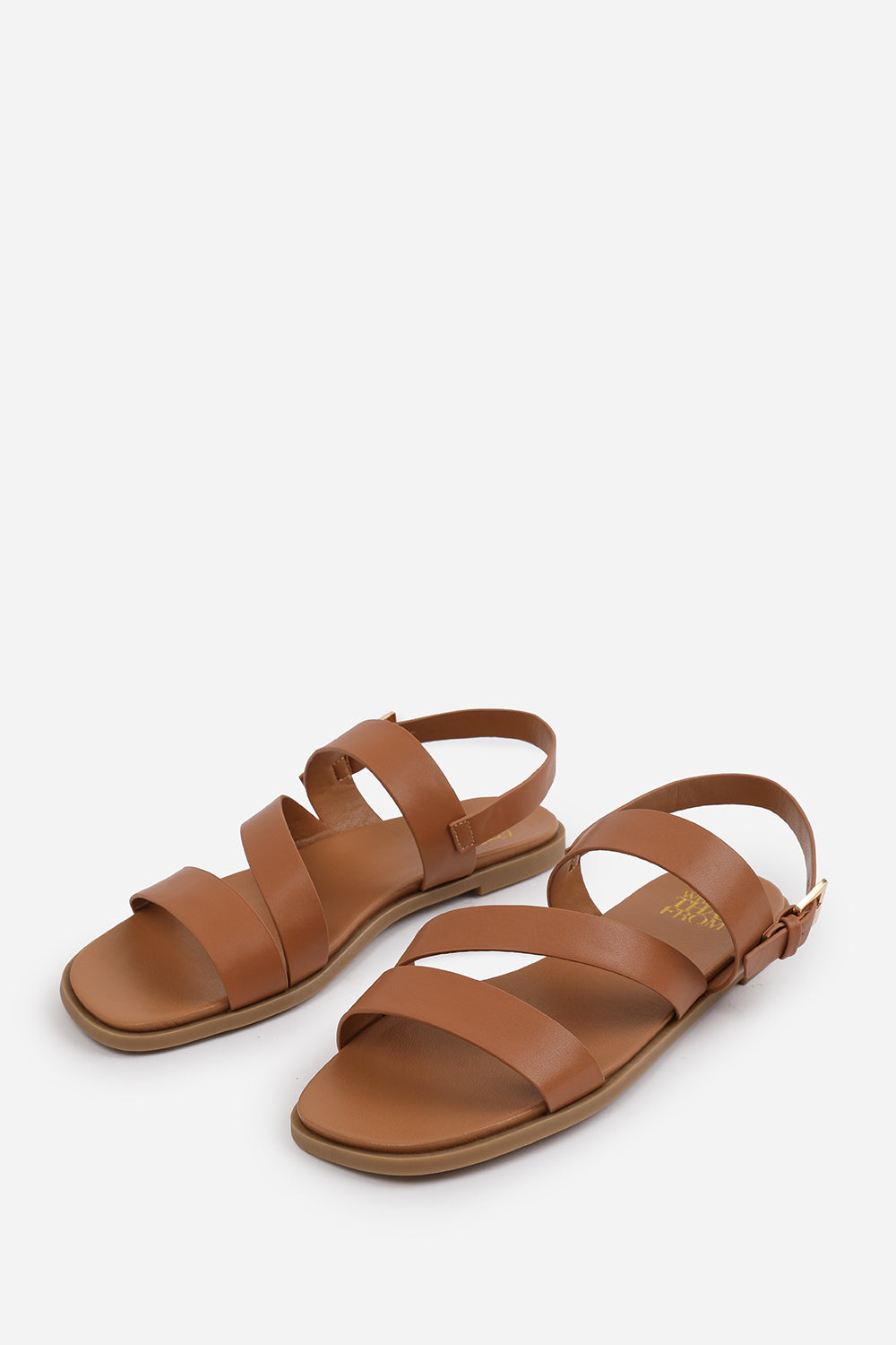 NESSA FLAT SANDALS WITH CROSS OVER STRAP AND BUCKLE CLOSURE IN TAN FAUX LEATHER