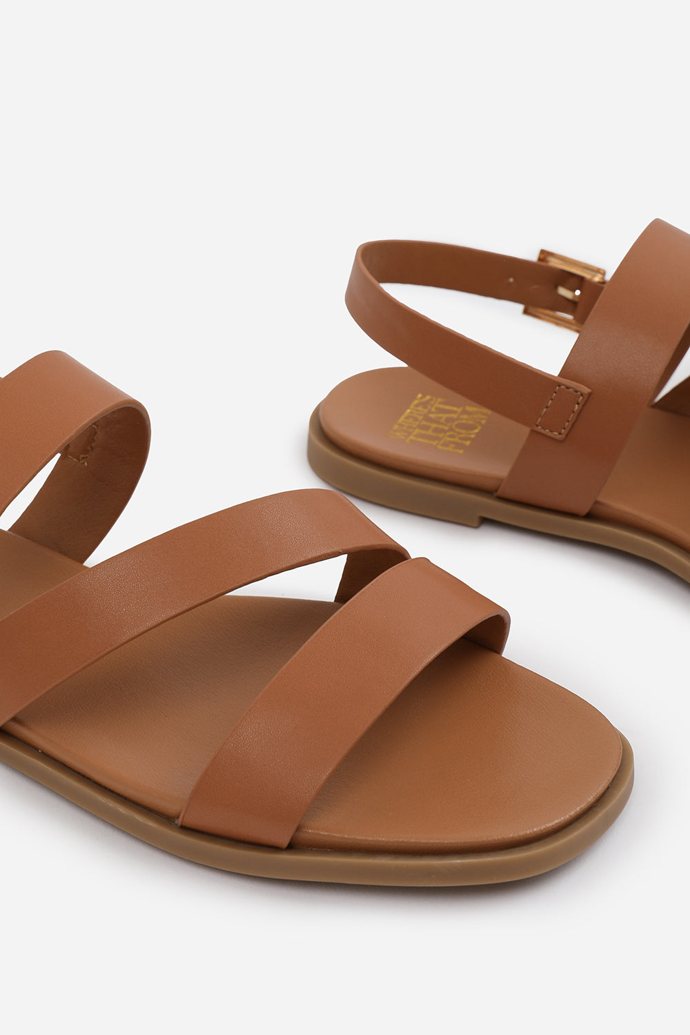 NESSA WIDE FIT FLAT SANDALS WITH CROSS OVER STRAP AND BUCKLE CLOSURE IN TAN FAUX LEATHER