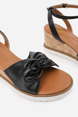 KATARA WIDE FIT KNOT DETAIL WEDGE SHOES WITH BUCKLE ANKLE STRAP IN BLACK PU