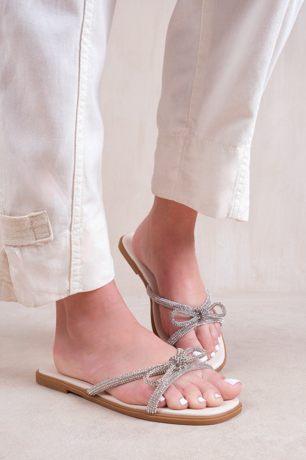 EARTH FLAT SLIP ON SANDALS WITH BOW DIAMANTE DETAIL IN CREAM FAUX LEATHER
