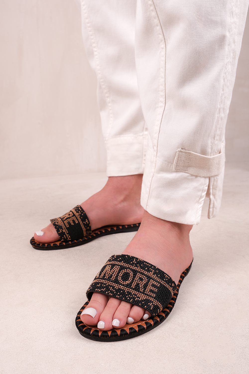 NOTE STRAP FLAT SANDALS WITH BEADED TEXT DETAIL IN BLACK FAUX LEATHER